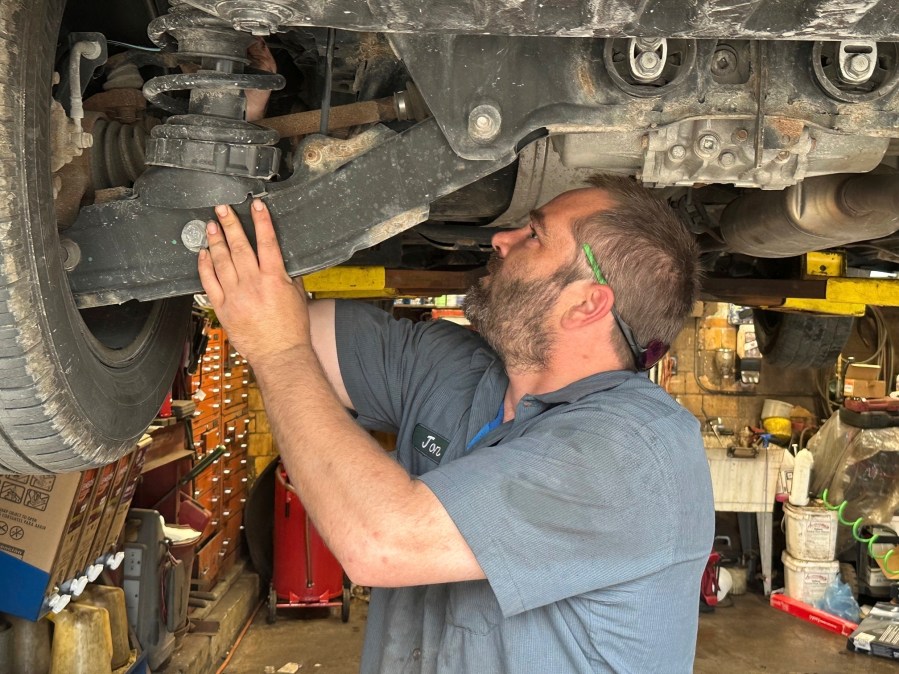 CORRECTS YEAR IN SECOND SENTENCE TO 2023 Mechanic Jon Guthrie inspects the underside of a 2014 Honda Ridgeline pickup truck at Japanese Auto Professional Service in Ann Arbor, Michigan. People are keeping their vehicles longer due to shortages of new ones and high prices. That drove the average U.S. vehicle age up to a record 12.5 years in 2023, according to S&P Global Mobility. (AP Photo/Tom Krisher)