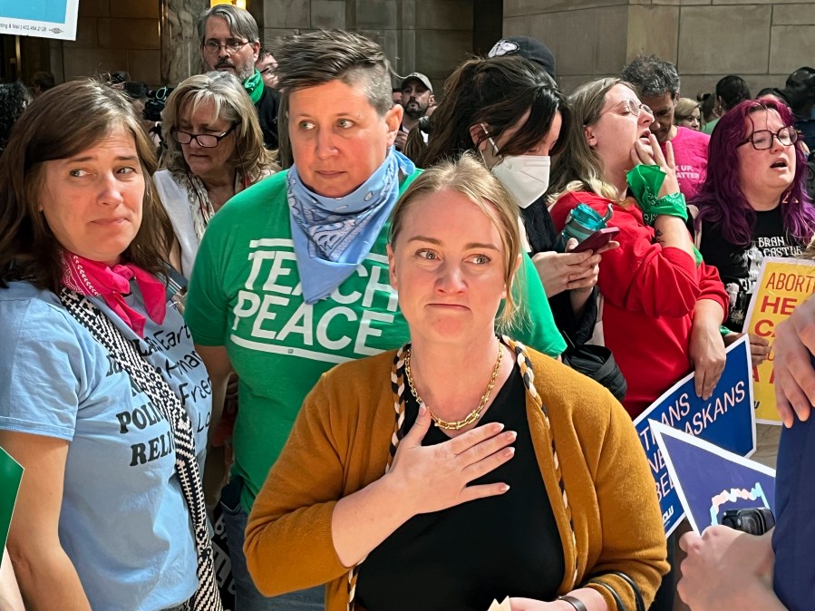 Nebraska state Sen. Megan Hunt, center, stands among supporters minutes after a vote in which the Nebraska Legislature passed a bill to ban abortion at 12 weeks and ban gender-affirming care in minors, Friday, May 19, 2023 in Lincoln, Neb.. The crowd raucously protested the bill in the Capitol rotunda as lawmakers debated it. Hunt has been a vocal opponent of the bans. (AP Photo/Margery Beck)