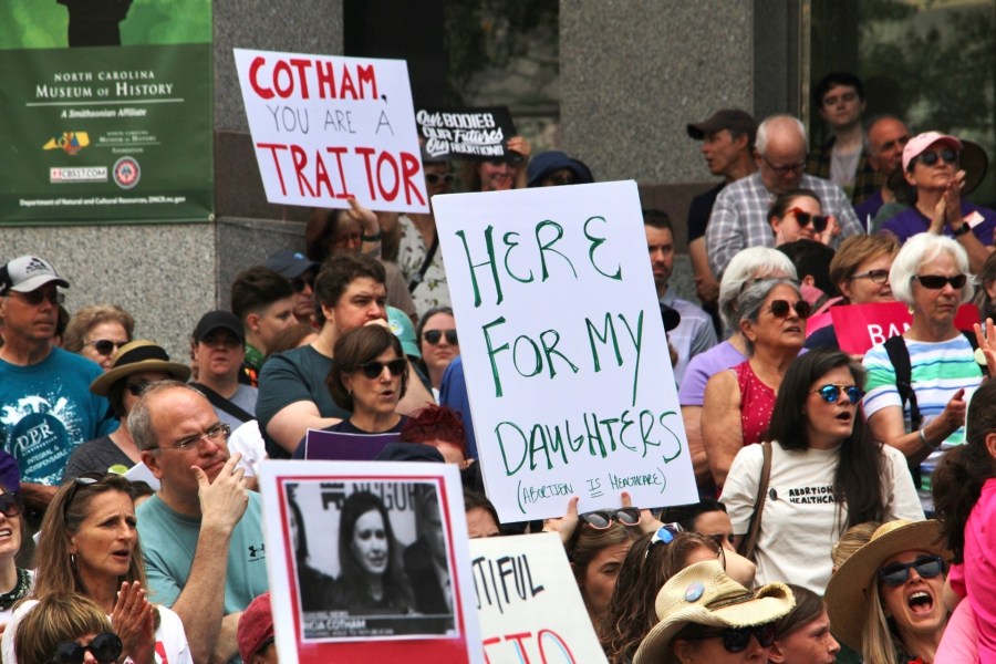 Abortion rights protesters hold up signs criticizing North Carolina state Rep. Tricia Cotham, whose party switch from Democrat to Republican gave the GOP a veto-proof supermajority, at a rally in Raleigh, N.C., Saturday, May 13, 2023. (AP Photo/Hannah Schoenbaum)