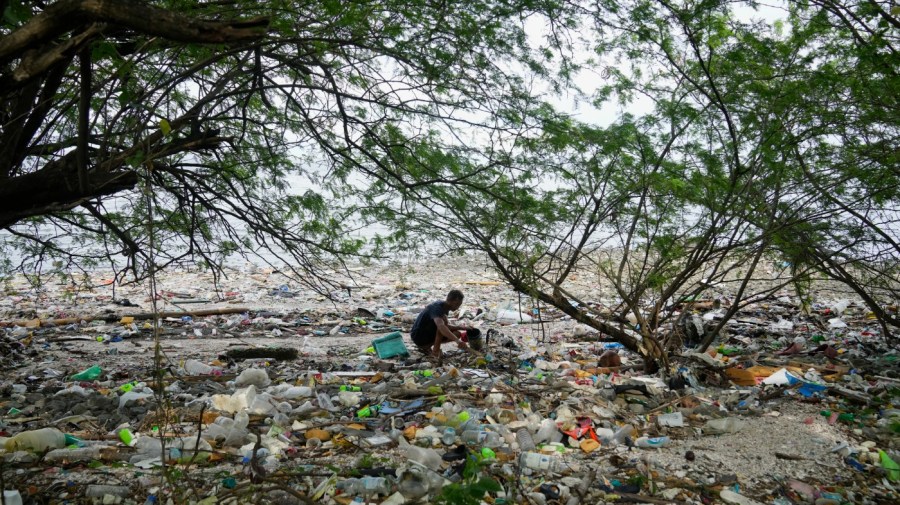 FILE - A man collects items along a polluted coastal area in Metro Manila, Philippines, Sept. 16, 2022. More than 2,000 experts plan to wrap up early negotiations Friday, Dec. 2, on plastic pollution at one of the largest global gatherings ever to address the crisis. (AP Photo/Aaron Favila, File)