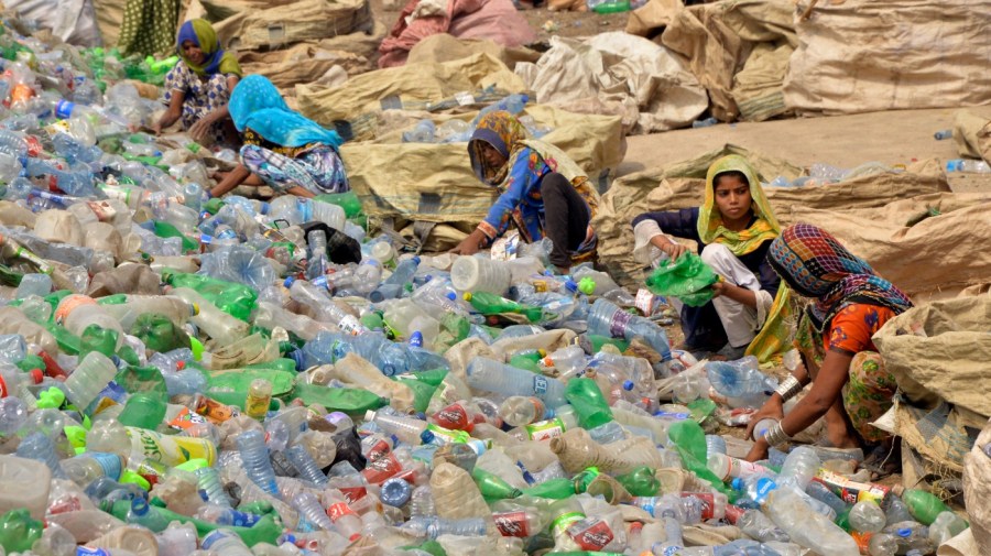 Pakistani laborers, mostly women, sort through empty bottles at a plastic recycling factory in Hyderabad, Pakistan, Sunday, April 30, 2023. (AP Photo/Pervez Masih)