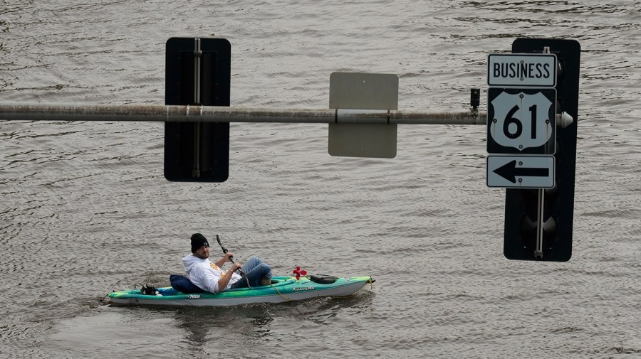 A kayaker floats down a flooded street