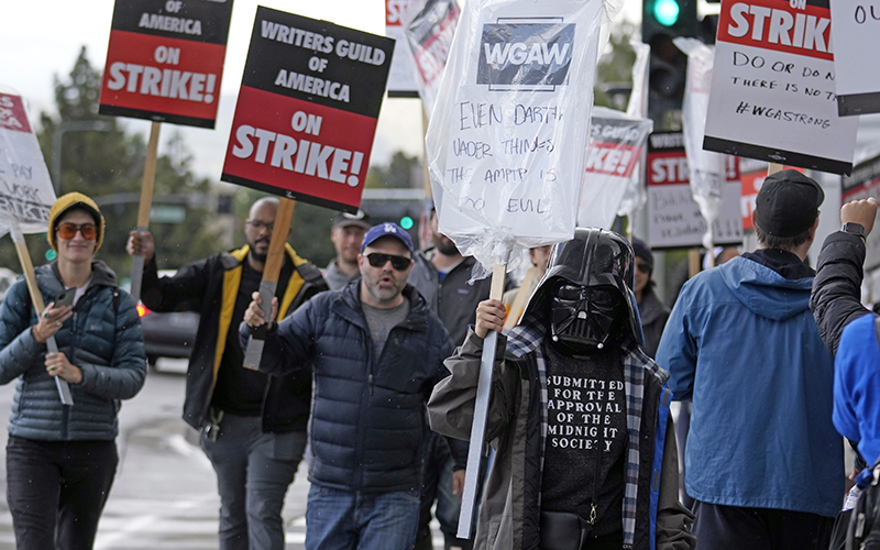 Writer Montserrat Luna-Ballantyne, right, wears a Darth Vader mask while picketing