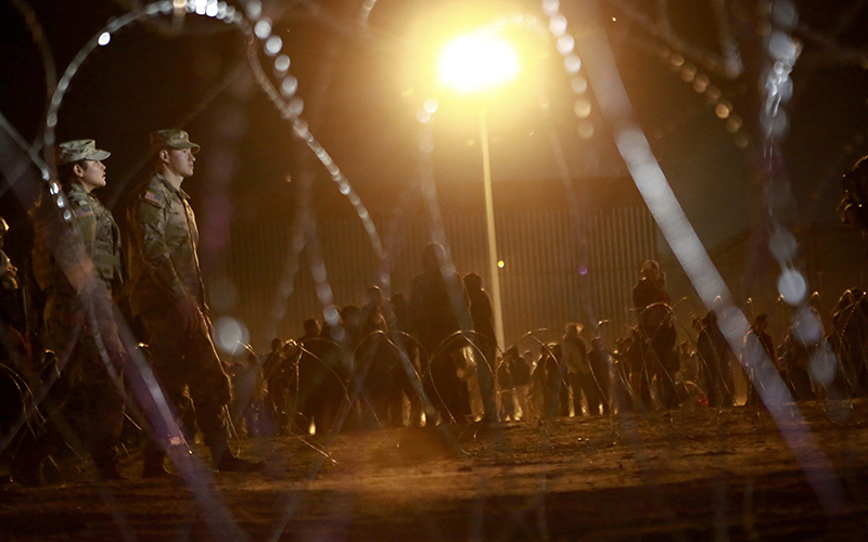 Migrants wait for U.S. authorities at gate 42, between a barbed-wire barrier and the border fence