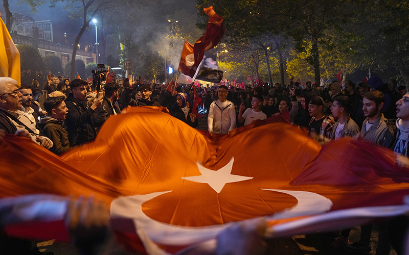 Supporters of President Recep Tayyip Erdogan celebrate outside as they hold a large Turkish flag