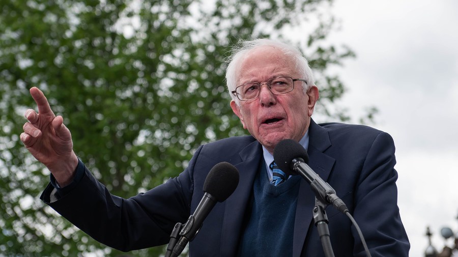 Senator Bernie Sanders speaks into microphones during an announcement.