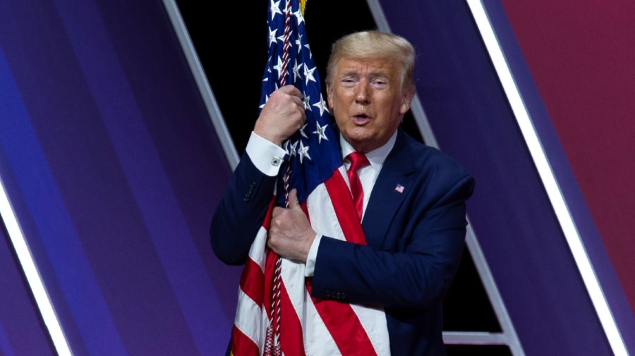 In this Feb. 29, 2020 file photo, President Trump hugs and kisses the American flag after speaking at Conservative Political Action Conference, CPAC 2020, at the National Harbor, in Oxon Hill.