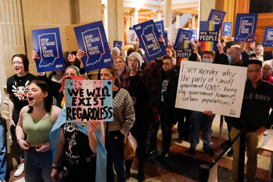 FILE - Protesters stand outside of the Senate chamber at the Indiana Statehouse on Feb. 22, 2023, in Indianapolis. A federal judge is scheduled Wednesday, June 14, to hear arguments in a lawsuit seeking to block an Indiana law banning doctors from providing puberty blockers, hormones and gender-affirming surgeries to minors. (AP Photo/Darron Cummings, File)