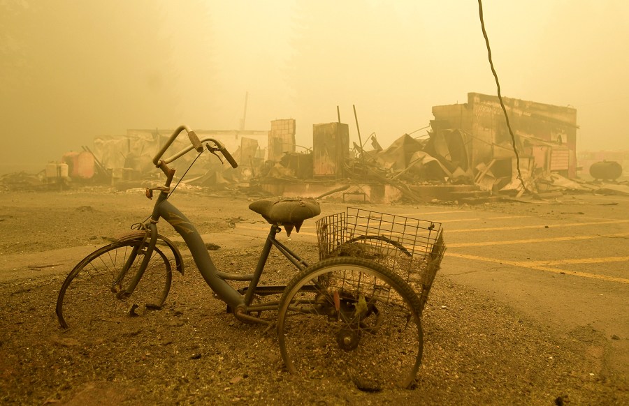 FILE - A trike stands near the burnt remains of a building destroyed by a wildfire near the Lake Detroit Market in Detroit, Ore., Sept. 11, 2020. A jury verdict that found power company PacifiCorp liable for devastating wildfires in Oregon in 2020 is highlighting the legal and financial risks utilities face if they fail to take proper precautions for climate change. (Mark Ylen/Albany Democrat-Herald via AP, File)