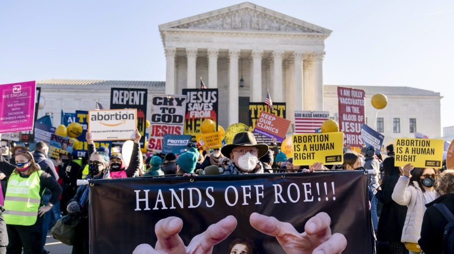 FILE -Stephen Parlato of Boulder, Colo., holds a sign that reads "Hands Off Roe!!!" as abortion rights advocates and anti-abortion protesters demonstrate in front of the U.S. Supreme Court, Wednesday, Dec. 1, 2021, in Washington. One year ago, the U.S. Supreme Court rescinded a five-decade-old right to abortion, prompting a seismic shift in debates about politics, values, freedom and fairness. (AP Photo/Andrew Harnik, File)