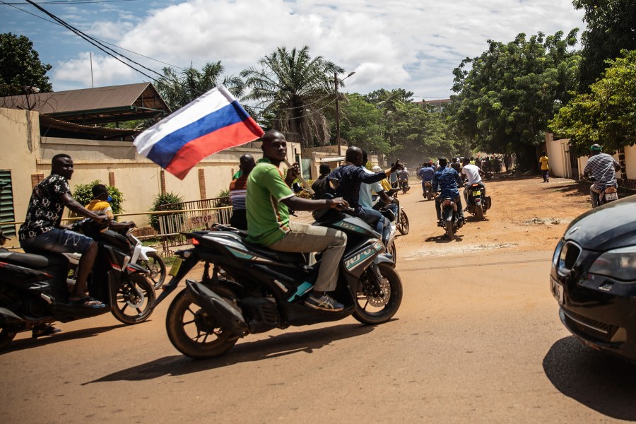 FILE - Supporters of Capt. Ibrahim Traore parade wave a Russian flag in the streets of Ouagadougou, Burkina Faso, Oct. 2, 2022. The Russian mercenary group that briefly rebelled against President Vladimir Putin’s authority has for years been a ruthless force-for-hire across Africa, protecting rulers at the expense of the masses. That dynamic is not expected to change now that the group’s founder, Yevgeny Prigozhin, has been exiled to Belarus as punishment for the failed rebellion. Neither Russia nor the African leaders dependent on Wagner’s fighters have any interest in ending their relationships. (AP Photo/Sophie Garcia, File)