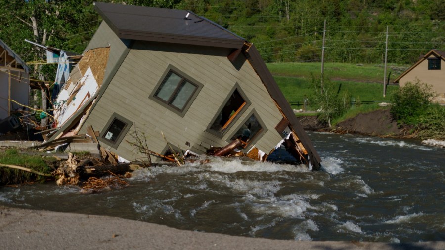 A house sits in Rock Creek after floodwaters washed away a road and a bridge in Red Lodge, Mont., June 15, 2022. (AP Photo/David Goldman, File)