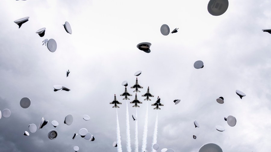 Graduates' hats fill the air as jets fly over the Air Force Academy graduation ceremony