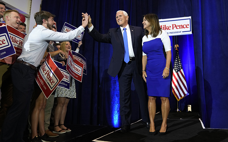 Former Vice President Mike Pence high-fives a supporter as he and his wife arrive to speak at a campaign event