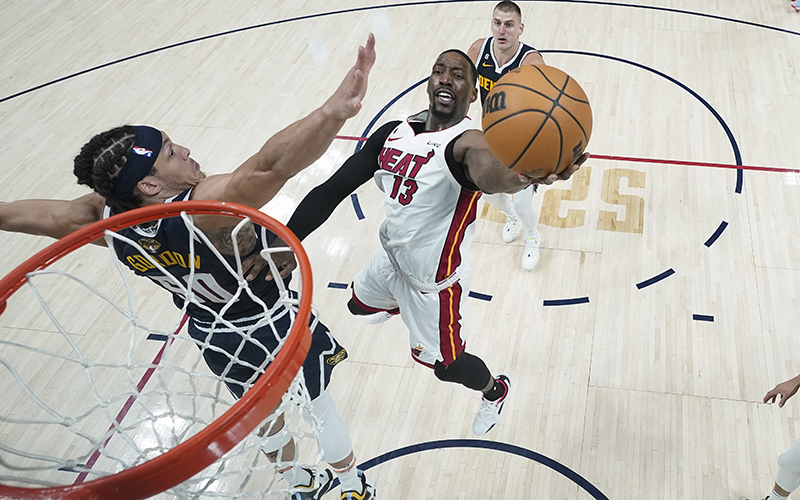 A view from just above the basketball hoop shows as Miami Heat center Bam Adebayo (13) shoots the ball while defended by Denver Nuggets forward Aaron Gordon, to the left.