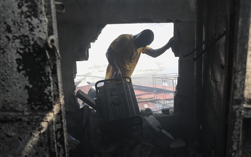 A man attempts to remove a generator through a hole in a building wall in the aftermath of a fire