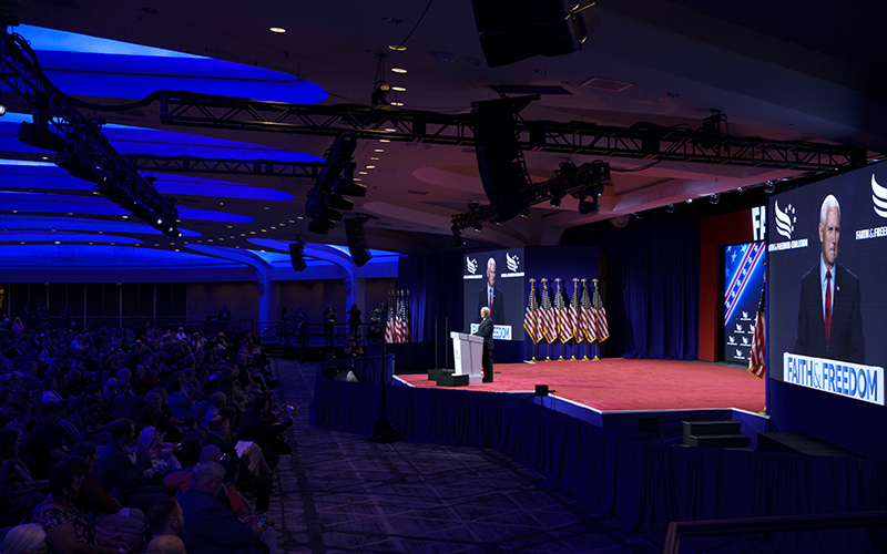 Republican presidential candidate and former Vice President Mike Pence addresses the Faith and Freedom Coalition's Road to Majority conference. The picture is taken from a distance, showing the stage and attendees