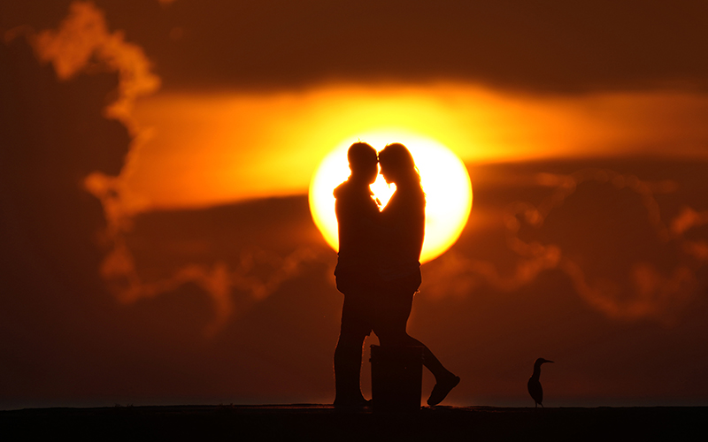 A couple watches the sun rise over the Atlantic Ocean