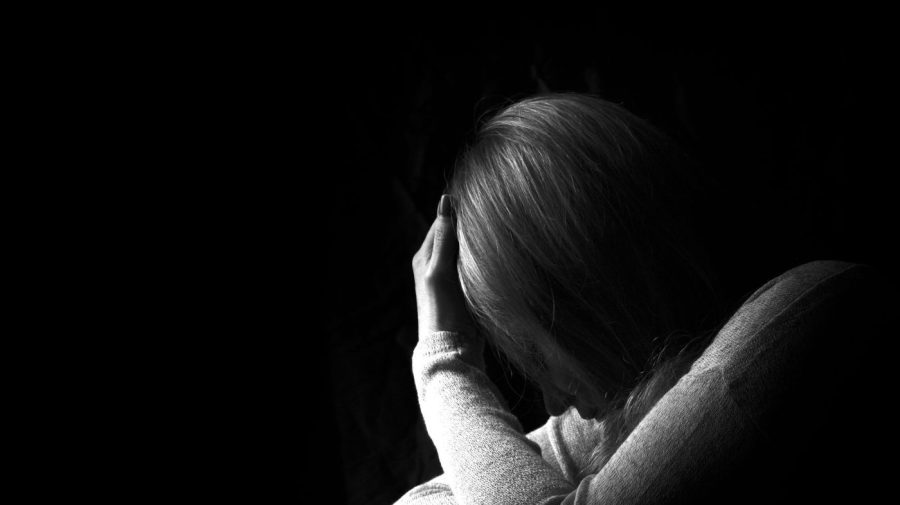 Black and white portrait of a woman hiding her face with hands.