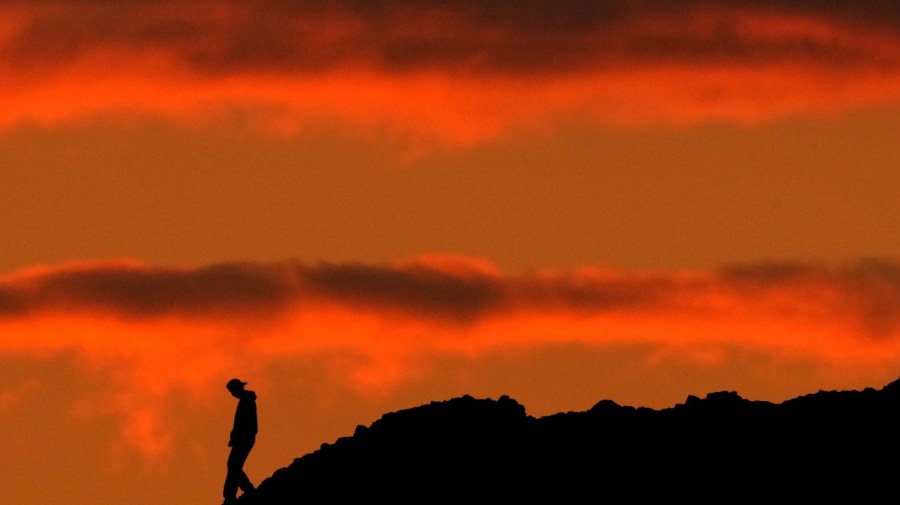 A person is silhouetted against the sky at sunset at Papago Park in Phoenix on Thursday, March 2, 2023. The homicide rate for older U.S. teenagers rose to its highest point in nearly 25 years during the COVID-19 pandemic, and the suicide rate for adults in their early 20s was the worst in more than 50 years, government researchers said Thursday, June 15. (AP Photo/Charlie Riedel)