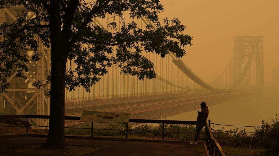 FILE - A man talks on his phone as he looks through the haze at the George Washington Bridge in Fort Lee, N.J., June 7, 2023. As smoky as the summer has been so far, scientists say it will likely be worse in future years because of climate change. (AP Photo/Seth Wenig, File)