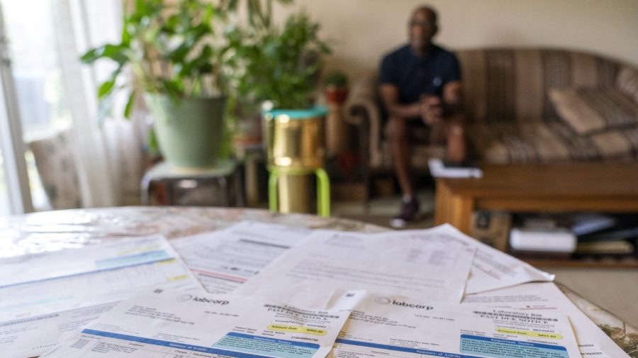 David White, who after kidney surgery got hit with a lot of extra charges, sits for a portrait with some of his medical bill charges in the foreground, at his home in Temple Hills, Md., Monday, June 26, 2023. The Patient Advocate Foundation helped him recoup more than $2,000 he paid for routine lab work. “Every single penny that I paid out was refunded,” said the 61-year-old White, a volunteer foundation board member. “There’s just no way I could figure this out on my own.” (AP Photo/Jacquelyn Martin)