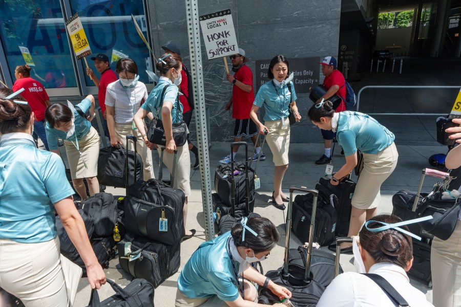 Korean Air Airlines flight attendants get off their bus on the street sidewalk of the InterContinental Los Angeles Downtown as striking hotel workers rally outside Monday, July 3, 2023, in downtown Los Angeles. (AP Photo/Damian Dovarganes)