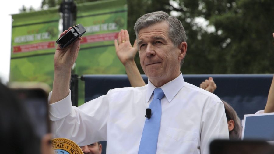 FILE - North Carolina Democratic Gov. Roy Cooper affixes his veto stamp to a bill banning nearly all abortions after 12 weeks of pregnancy at a public rally, May 13, 2023, in Raleigh, N.C. On Wednesday, July 5, Cooper vetoed a trio of bills aimed at LGBTQ+ youth that would ban gender-affirming health care for minors, restrict transgender participation in school sports and limit classroom instruction about gender identity and sexuality. (AP Photo/Hannah Schoenbaum, File)