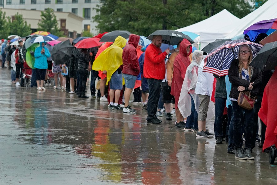 People wait in the rain ahead of a rally for former President Donald Trump, Friday, July 7, 2023, in Council Bluffs, Iowa. (AP Photo/Charlie Riedel)