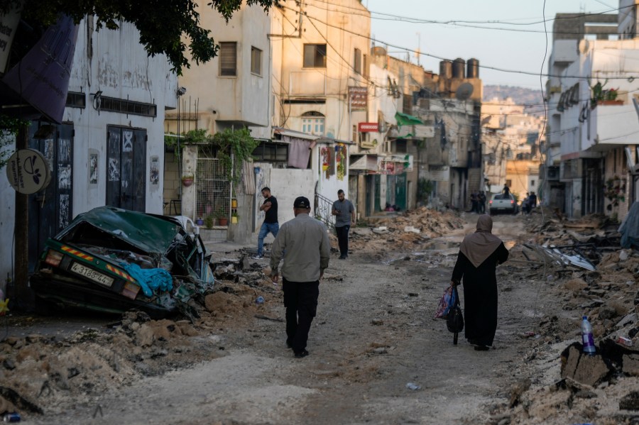 Palestinians walk on a damaged road following two days of Israeli military raid on the militant stronghold of the Jenin refugee camp in the West Bank, Wednesday, July 5, 2023. The Israeli military says it has withdrawn its troops from the refugee camp. The pullout Wednesday morning ended an intense two-day operation that killed at least 13 Palestinians, drove thousands of people from their homes and left a wide swath of damage in its wake. One Israeli soldier was also killed. (AP Photo/Majdi Mohammed)