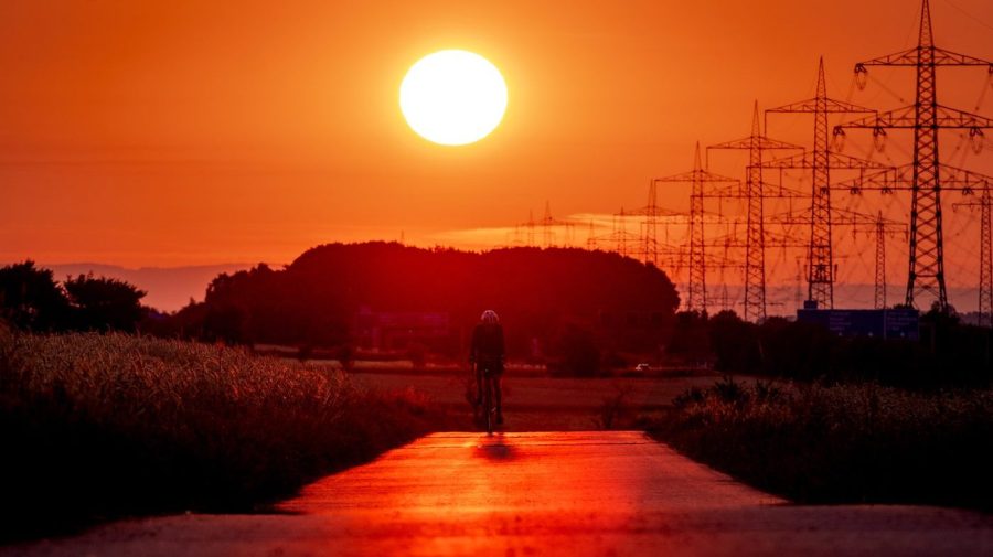 FILE - A man rides his bike on a small road in the outskirts of Frankfurt, Germany, as the sun rises on July 9, 2023. Scientists say crushing temperatures that blanketed Europe last summer may have led to more than 61,000 heat-related deaths, highlighting the need for governments to address the health impacts of global warming. (AP Photo/Michael Probst, File)