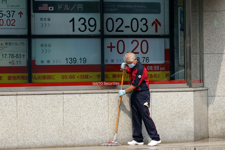 A worker sweeps in front of an electronic stock board showing U.S. dollar/Japanese yen exchange rate at a securities firm Wednesday, July 19, 2023, in Tokyo. Asian shares are mixed after Wall Street’s frenzy around artificial intelligence helped pushed U.S. stocks to their best level in more than 15 months. (AP Photo/Eugene Hoshiko)