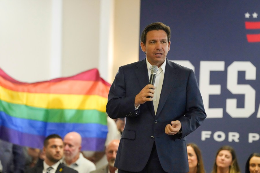 Protesters unfold and raise a rainbow flag behind Republican presidential candidate Florida Gov. Ron DeSantis as he speaking during a campaign event on Monday, July 17, 2023, in Tega Cay, S.C. (AP Photo/Meg Kinnard)