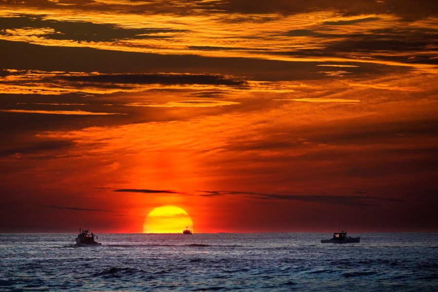 FILE - The sun rises over fishing boats in the Atlantic Ocean, Sept. 8, 2022, off of Kennebunkport, Maine. A system of ocean currents that carries heat northward across the North Atlantic could collapse during this century, according to a new study, and scientists have said before such a collapse could cause catastrophic sea-level rise and extreme weather across the globe. (AP Photo/Robert F. Bukaty, File)