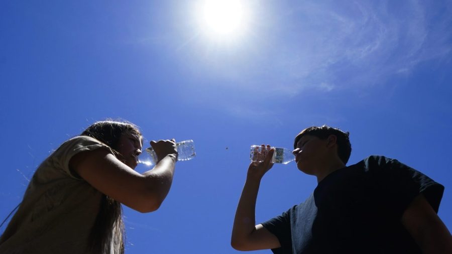 FILE - Tony Berastegui Jr., right, and his sister Giselle Berastegui drink water, Monday, July 17, 2023, in Phoenix. A historic heat wave that turned the Southwest into a blast furnace throughout July is beginning to abate with the late arrival of the monsoon rains. Forecasters expect that by Monday, July 31, at the latest, people in metro Phoenix will begin seeing high temperatures under 110 degrees Fahrenheit (43.3 degrees Celsius) for the first time in a month. (AP Photo/Ross D. Franklin, File)