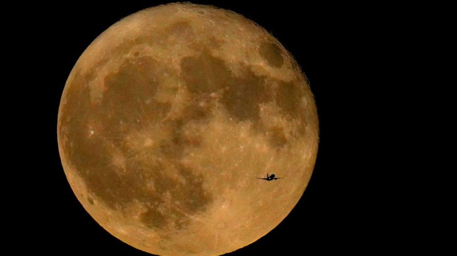 FILE - A commercial airliner flies Northwest across Lake Michigan in front of the "Full Buck" supermoon, the first of four supermoons in 2023, July 3, 2023, in Chicago.