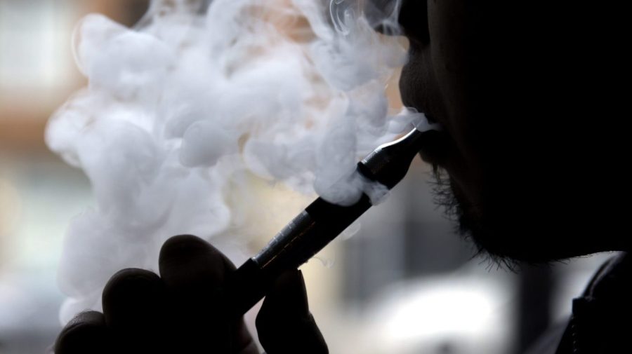 A puff of smoke billows as a person uses in e-cigarette.