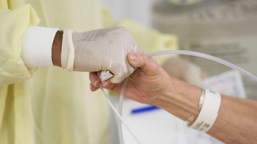 A doctor holds a patient's hand in the Covid-19 alternative care site, built into a parking garage, at Renown Regional Medical Center, December 16, 2020 in Reno, Nev.