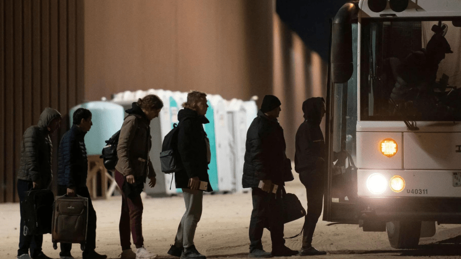 Asylum-seekers board a bus after being processed by US Customs and Border Patrol agents at a gap in the US-Mexico border fence.