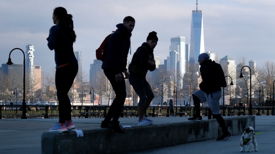 People exercise outdoors with a view of Manhattan in Hoboken, N.J., March 17, 2020. (AP Photo/Seth Wenig)