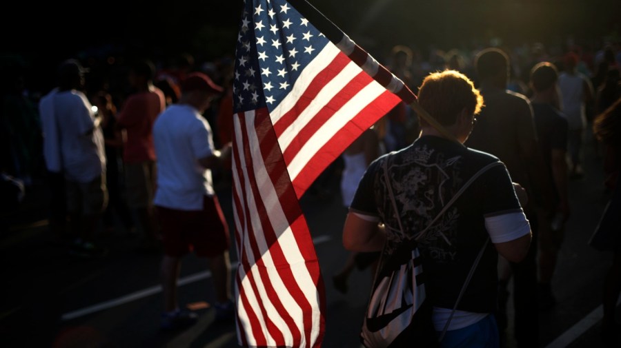 A young man walks with an American flag at an Independence Day celebration on the Benjamin Franklin Parkway, July 4, 2013, in Philadelphia. (AP Photo/Matt Rourke, File)