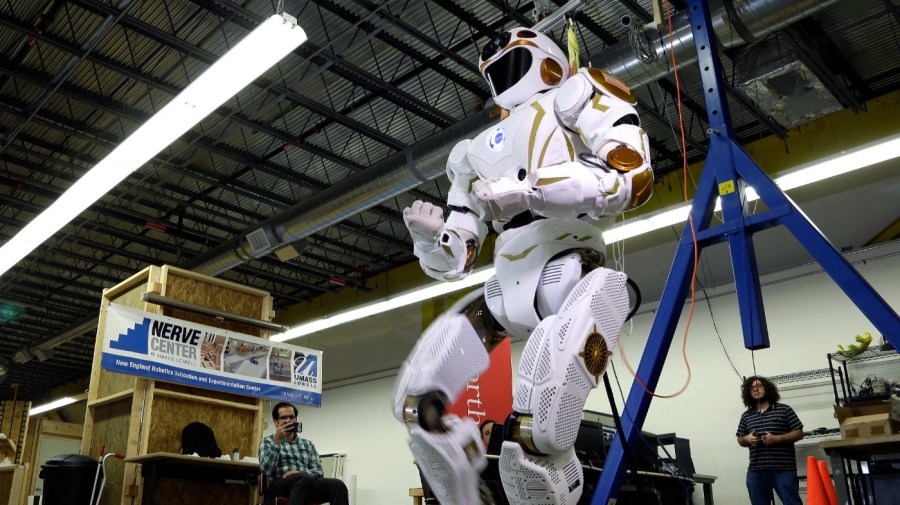 In this May 2, 2016 photo, researchers watch a six-foot-tall, 300-pound Valkyrie robot walk slowly at University of Massachusetts-Lowell's robotics center in Lowell, Mass. "Val," one of four sister robots built by NASA, could be the vanguard for the colonization of Mars by helping to set up a habitat for future human explorers. NASA spokesman Jay Bolden says the agency aims to get to Mars by 2035 and it’ll be the Valkyries or their descendants paving the way. (AP Photo/Elise Amendola)