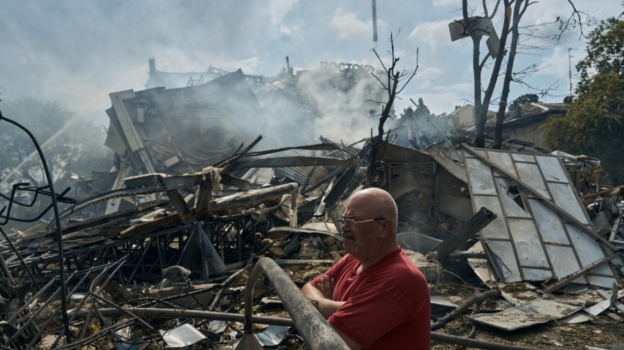 A man watches as emergency service personnel work at the site of a destroyed building after a Russian attack in Odesa, Ukraine, Thursday, July 20, 2023.