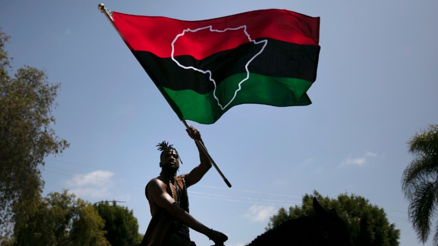 Rein Morton waves a Pan-African flag on horseback during a Juneteenth celebration in Los Angeles, Friday, June 19, 2020.