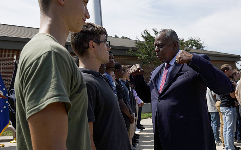 Secretary of Defense Lloyd Austin pumps his arms as he speaks to military recruits at an oath of enlistment ceremony