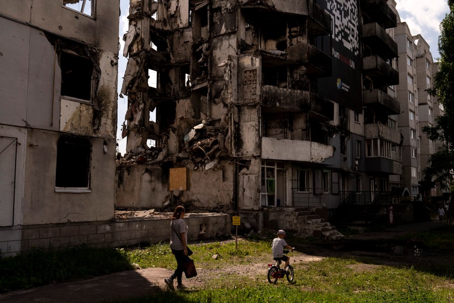 A woman and a boy make their way past an apartment building destroyed in Russian attacks in Borodyanka, Ukraine, Wednesday, Aug. 2, 2023. Borodyanka was occupied by Russian troops at the beginning of their full-scale invasion last year. (AP Photo/Jae C. Hong)