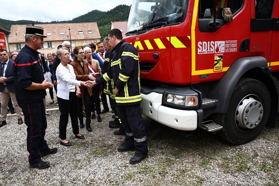 French Prime Minister Elisabeth Borne, 2nd left, shakes hands with a firefighter taking part in the rescue operations after a fire erupted at a holiday home for disabled people in Wintzenheim, France, Wednesday, Aug. 9, 2023. Eleven people have died after a fire ripped through a vacation home for adults with disabilities in eastern France. The deputy prosecutor of Colmar said 11 people who were sleeping on the upper floor and in a mezzanine area of the private accommodation were trapped by the fire, while five managed to escape. (Sebastien Bozon, Pool Photo via AP)