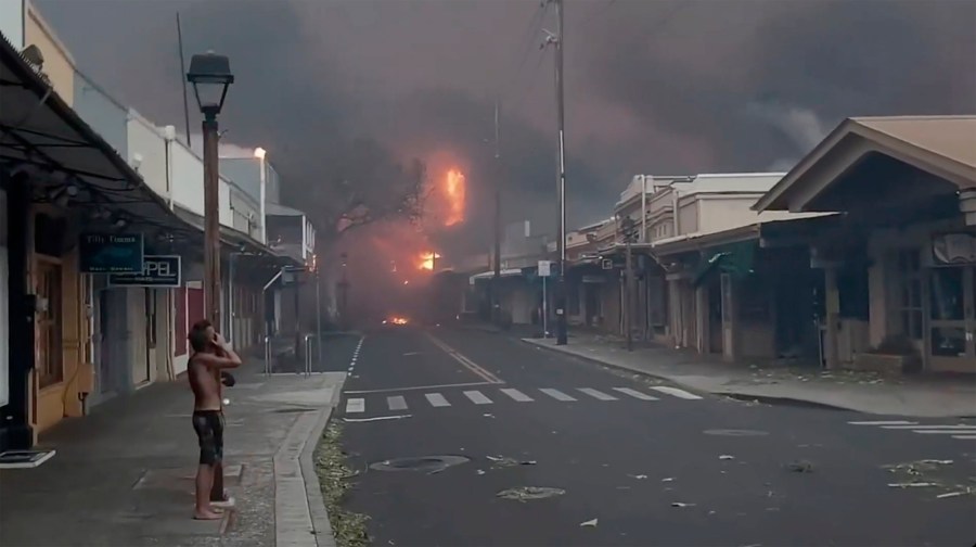 People watch as smoke and flames fill the air from raging wildfires on Front Street in downtown Lahaina, Maui on Tuesday, Aug. 8, 2023. Maui officials say wildfire in the historic town has burned parts of one of the most popular tourist areas in Hawaii. County of Maui spokesperson Mahina Martin said in a phone interview early Wednesday says fire was widespread in Lahaina, including Front Street, an area of the town popular with tourists. (Alan Dickar via AP