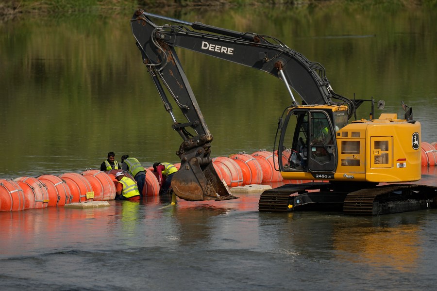 Workers make adjustments to buoys being used as a barrier along the Rio Grande, Monday, Aug. 21, 2023, in Eagle Pass, Texas. (AP Photo/Eric Gay)