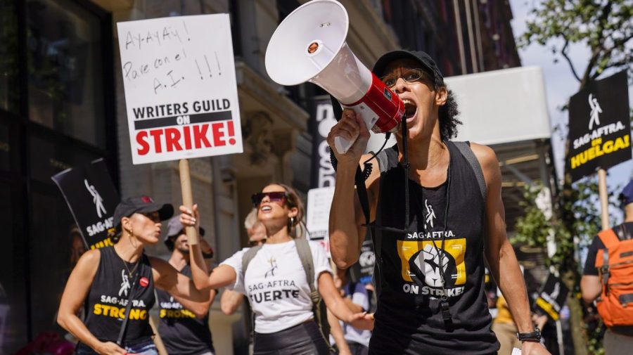 A strike captain, right, leads the chants as strikers walk a picket line outside Warner Bros., Discovery, and Netflix offices in Manhattan, Friday, Aug. 18, 2023. The WGA and SAG-AFTRA held a joint Latine Picket, presented by the WGAE Latine Writers Salon, the WGAW Latinx Writers Committee, and the SAG-AFTRA National Latino Committee. (AP Photo/Mary Altaffer)